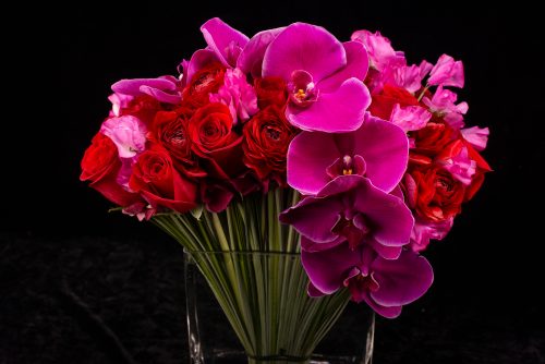 pink bouquet of orchids, roses and sweet peas in a clear vase