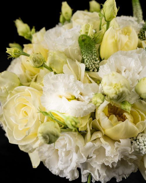 white roses, spring tulips, charming lisianthus, and veronica blooms in a white vase