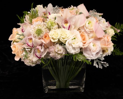 top view bouquet of roses, pale pink cymbidium orchids, scabiosa and calla lilies in a clear vase